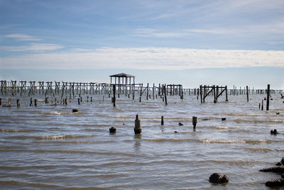 Wooden posts in sea against sky