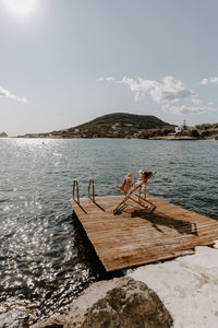 Rear view of woman sitting on pier by sea