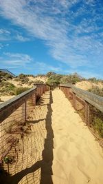 Walkway on sandy beach against sky