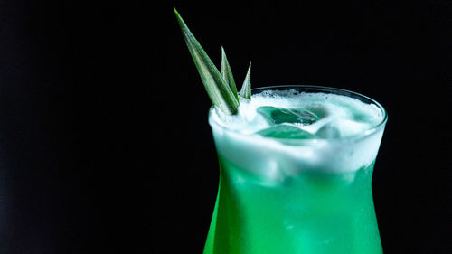 Green cocktail with ice on a black background