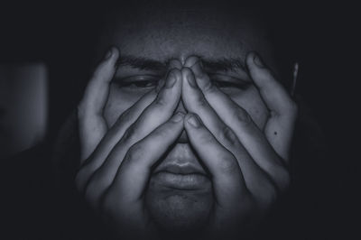 Close-up portrait of woman covering face with hand