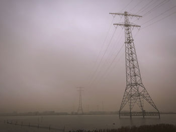 Low angle view of electricity pylon on field against sky