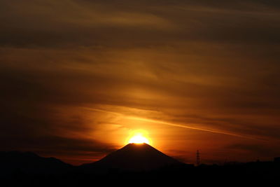 Scenic view of silhouette mountains against orange sky