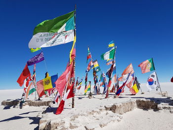 Low angle view of flags against clear blue sky