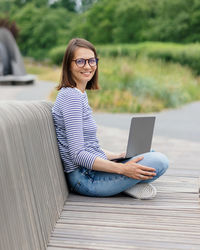 Female blogger in a public place works on a laptop or creates audio content for her subscribers