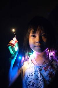 Portrait of a young woman holding sparkler at night