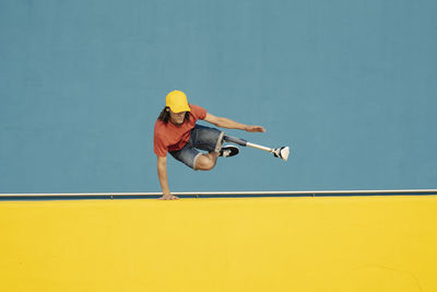 Disabled athlete doing handstand against multi colored wall