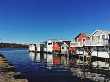 Stilt houses in lake against clear sky