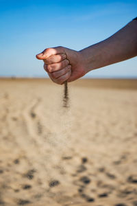 Midsection of man on sand at beach against sky