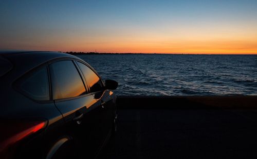 Close-up of car on sea against clear sky during sunset