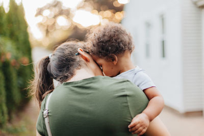 Young millennial mother and diverse mixed race toddler boy outdoors bonding together as family