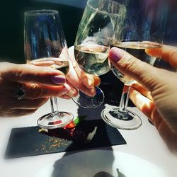 Close-up of hands holding wine glasses on table