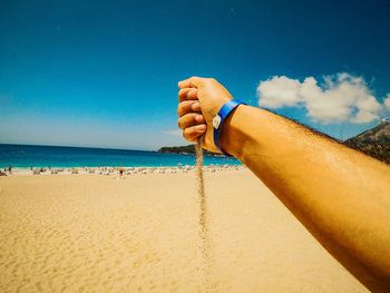 Low section of person on beach against sky