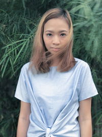 Portrait of young woman standing against plants