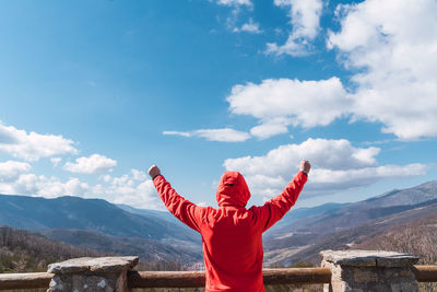 Caucasian unrecognizable male looking at the beautiful cloudy skies with mountains in the background