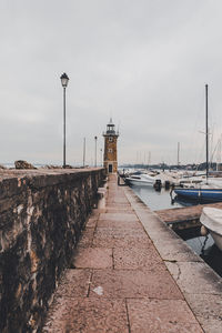 Sailboats moored at harbor against sky