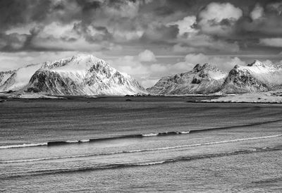 Scenic view of sea by mountains against sky