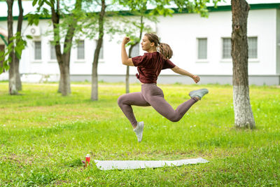 Full length of young woman jumping in field