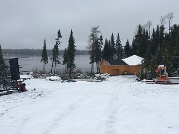 Snow covered field by houses against sky