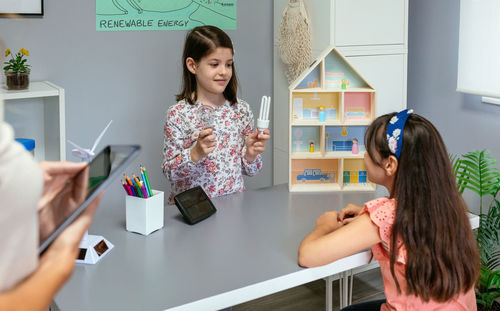 Student showing incandescent light bulb and led lamp in ecology classroom