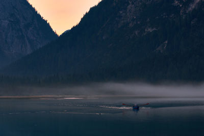 Scenic view of sea by mountain against sky