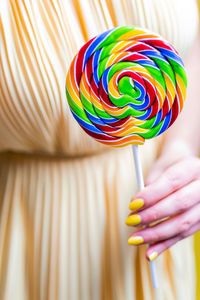 Close-up of hand holding multi colored lollipop