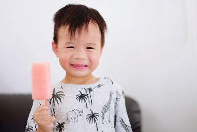 Portrait of boy eating popsicle while standing at home