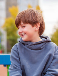 Cute caucasian boy casual wearing is sitting outdoors. portrait, blurred background