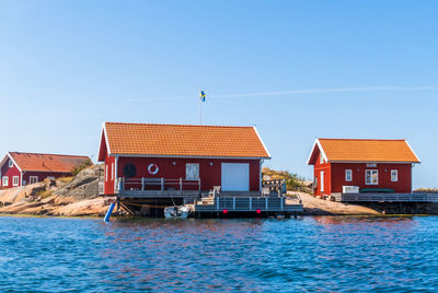 Houses by sea against clear blue sky