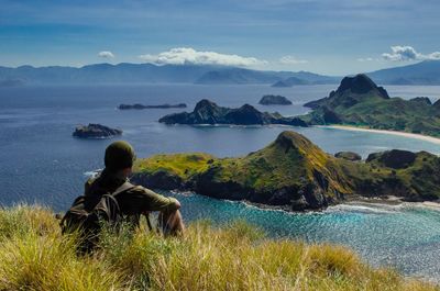 Man sitting at lake against sky