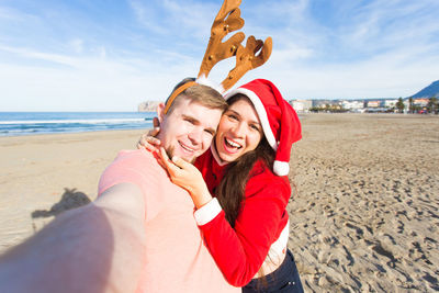 Portrait of smiling young woman at beach against sky