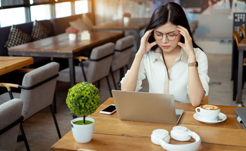 Businesswoman suffering from headache while sitting on table