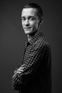 Portrait of young man standing against black background