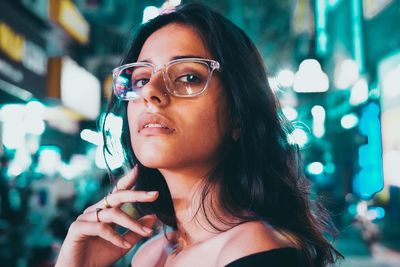 Beautiful young woman in illuminated city at night