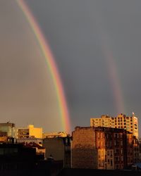 Rainbow over buildings in city against sky