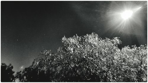 Low angle view of sun shining through clouds