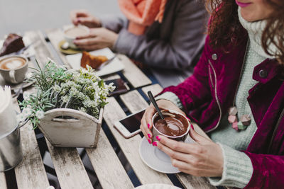 Midsection of woman holding ice cream on table