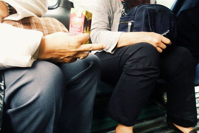 Midsection of people sitting on seat in train