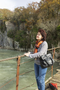 Woman standing by railing against trees