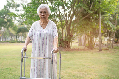 Portrait of senior woman holding walker at park