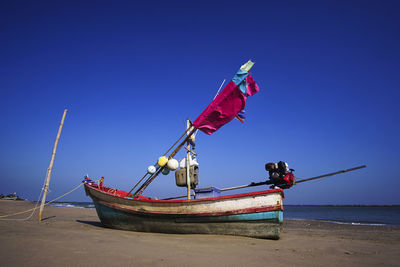 Ship moored on beach against clear blue sky