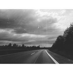 Country road against cloudy sky