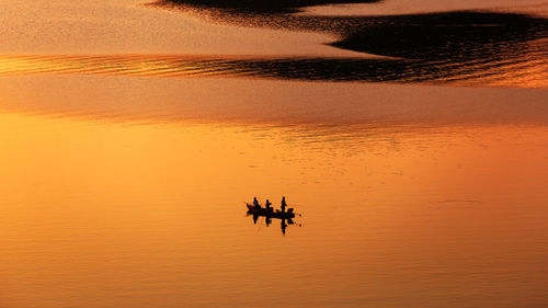 Fisherman fishing from the boat on the lake at sunset