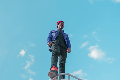 Low angle portrait of girl against blue sky
