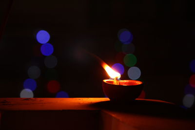 Close-up of illuminated diya on retaining wall