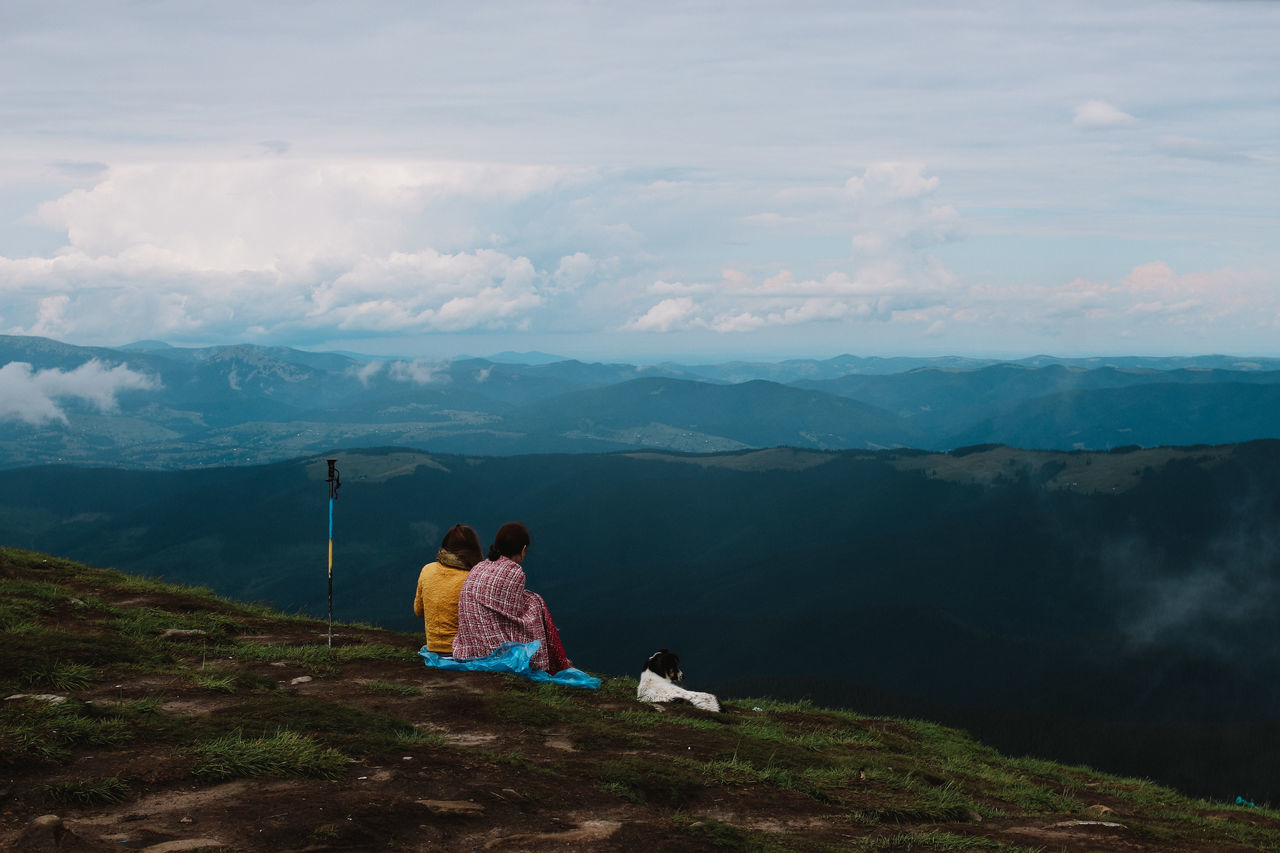 mountain, real people, pets, scenics - nature, leisure activity, domestic animals, beauty in nature, cloud - sky, domestic, sky, one animal, mammal, lifestyles, mountain range, rear view, nature, animal themes, tranquility, tranquil scene, outdoors, pet owner