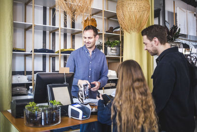 Father and daughter standing at checkout counter in boutique