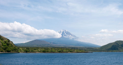 Scenic view of sea by mountains against sky