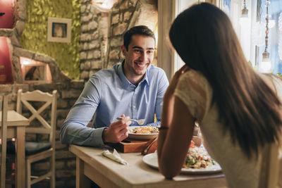 Portrait of happy young man having dinner with his girlfriend in a restaurant