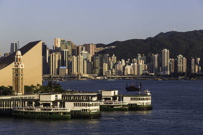 Sea and buildings in city against clear sky